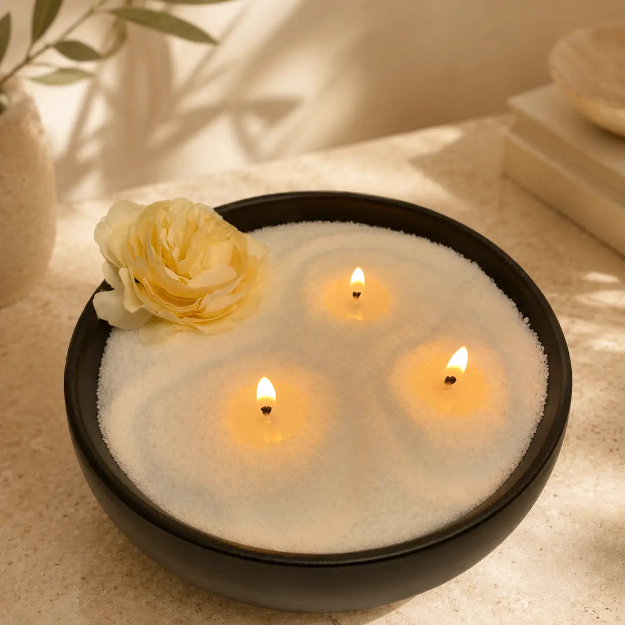 Soft white pearled candle wax burning in a black bowl with three glowing wicks and small melted wax pools, styled for Luster Candle