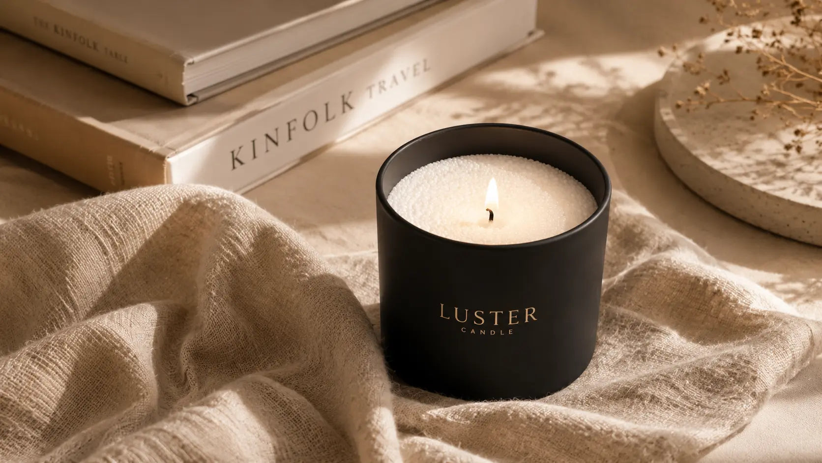 Soft white pearled candle wax in a modern black candle vessel on a warm beige linen surface