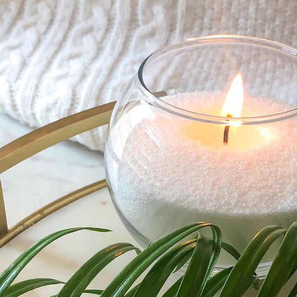Soft white pearled candle wax styled in a clear glass vessel with a lit wick, showing Luster Candle candle sand for modern home decor