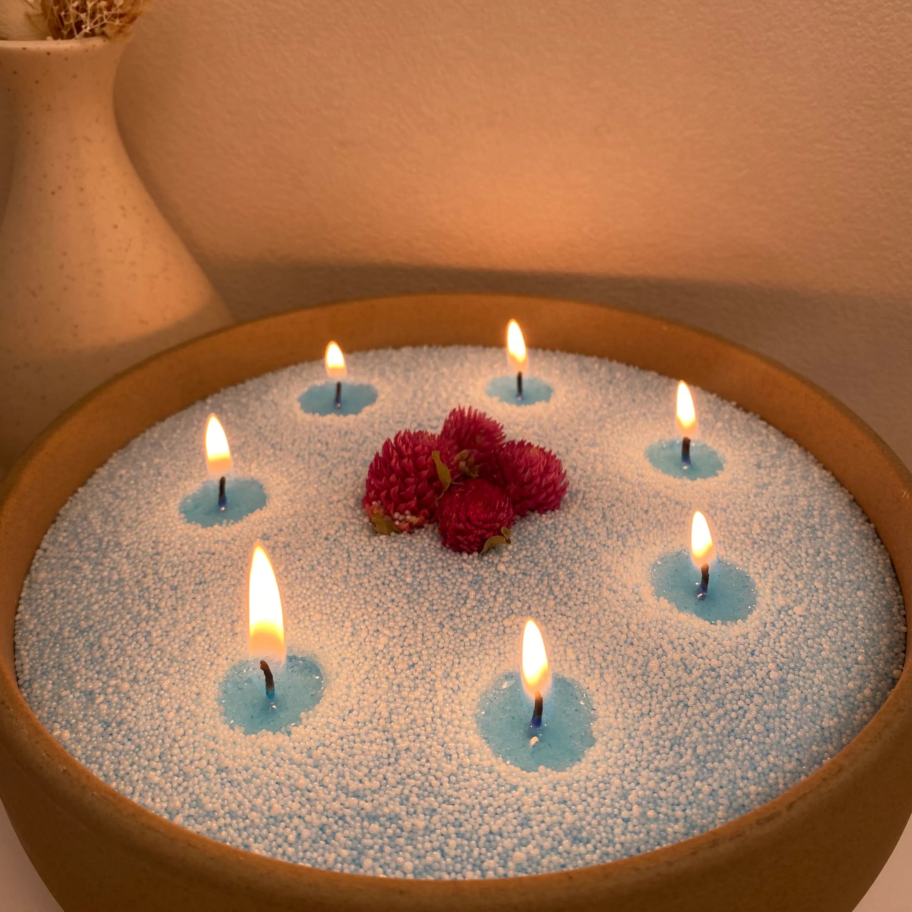 Baby Blue pearled candle wax in a ceramic candle bowl with soft flames and floral decor.
