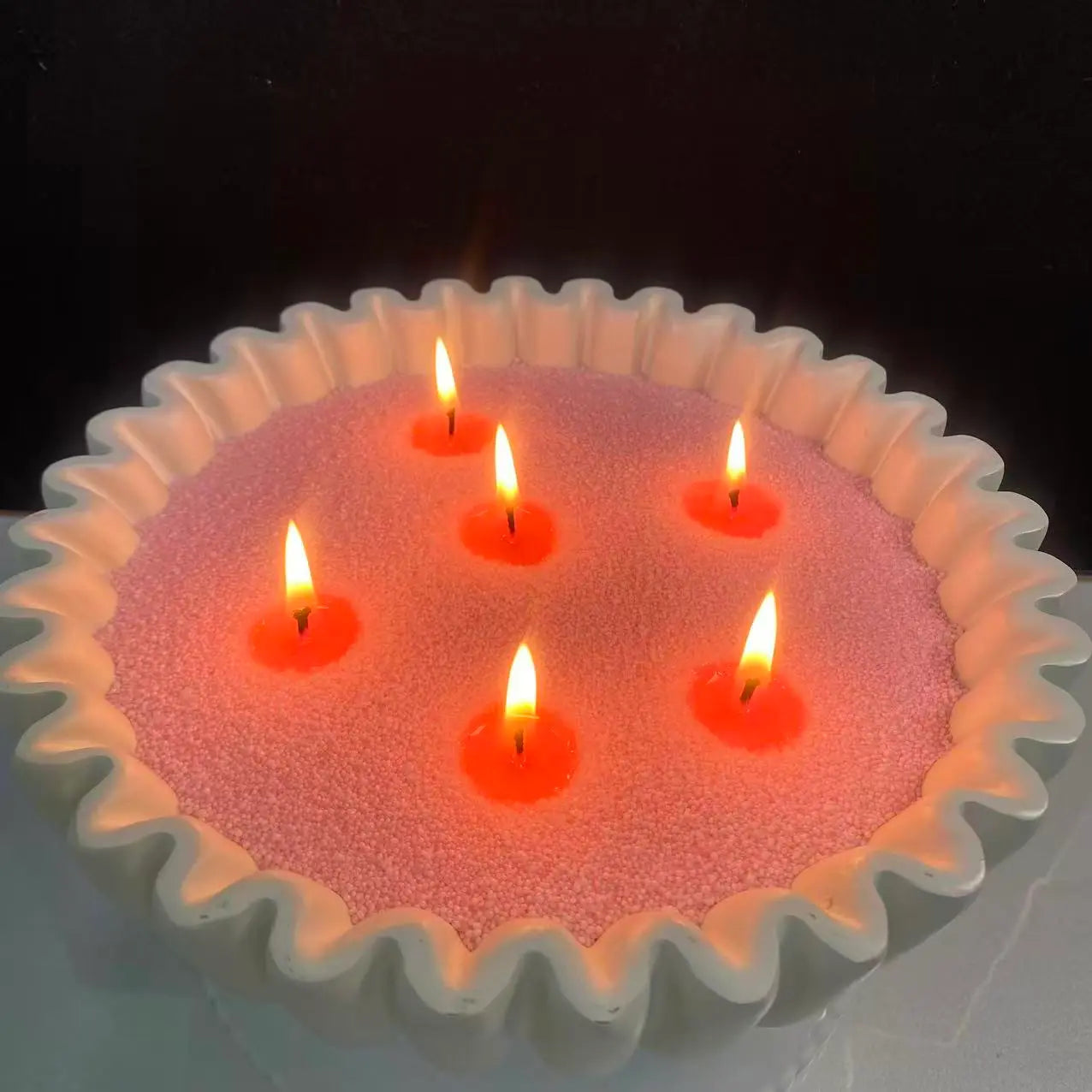 Blush Pink pearled candle wax in a white scalloped candle vessel with multiple warm flames and realistic melted wax around the wicks.