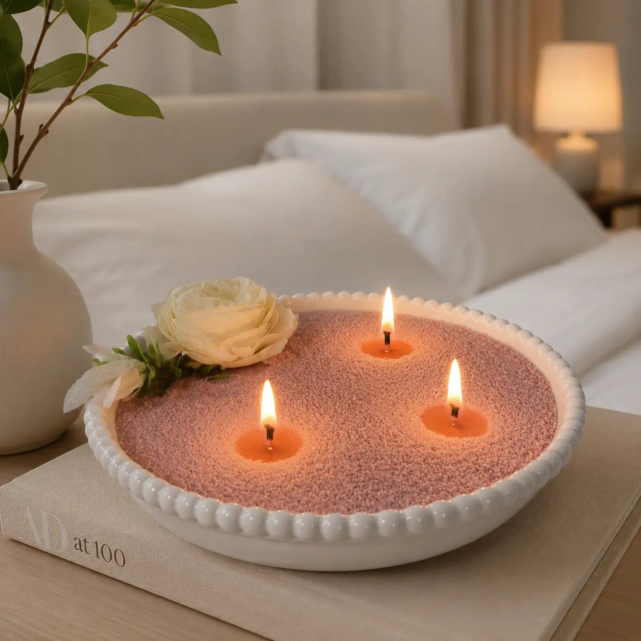 Large vessel filled with Blush Rose scented pearled candle wax and multiple lit wicks in a cozy bedroom setting