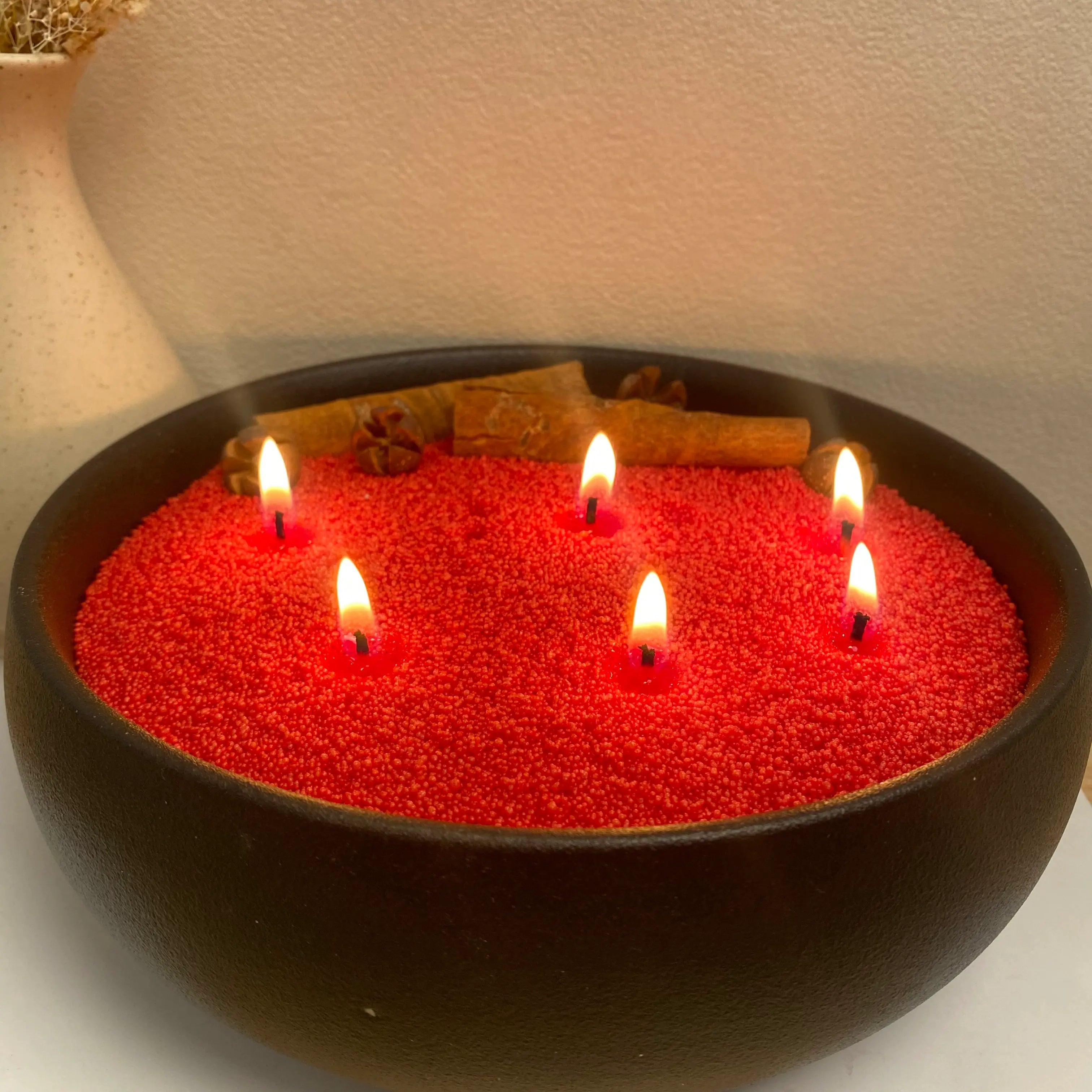 Burgundy Red pearled candle wax burning in a matte black round vessel with multiple cotton wicks.