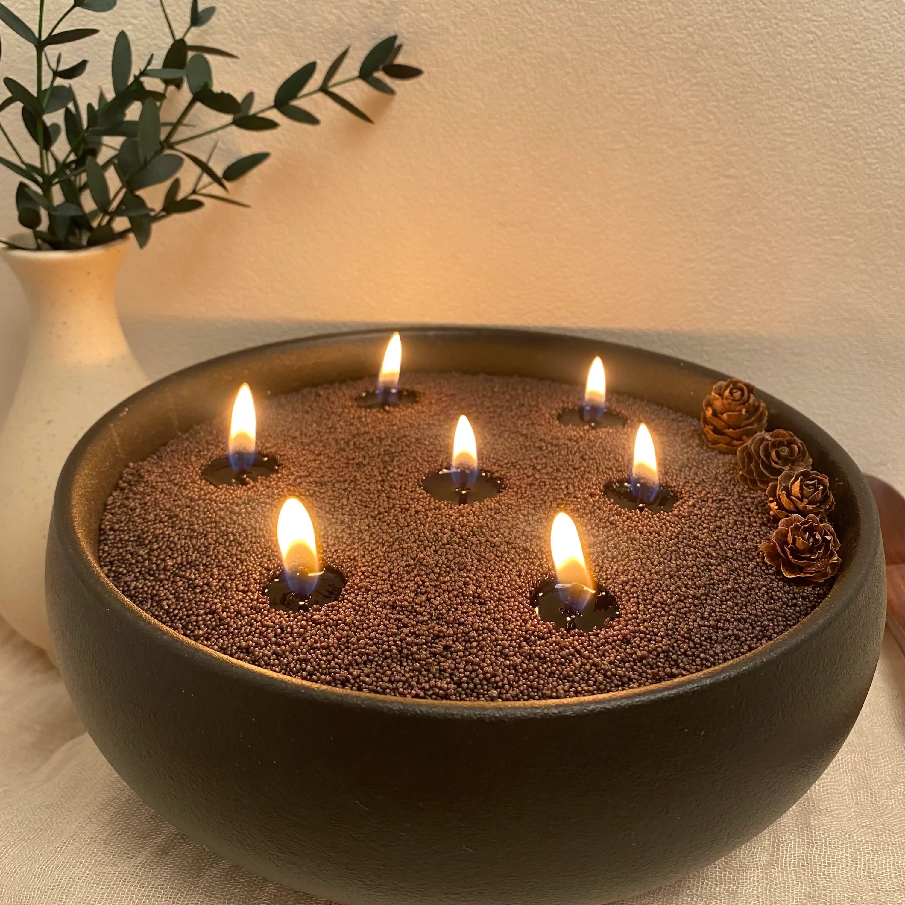 Charcoal Black pearled candle wax burning in a matte black round vessel with multiple cotton wicks.
