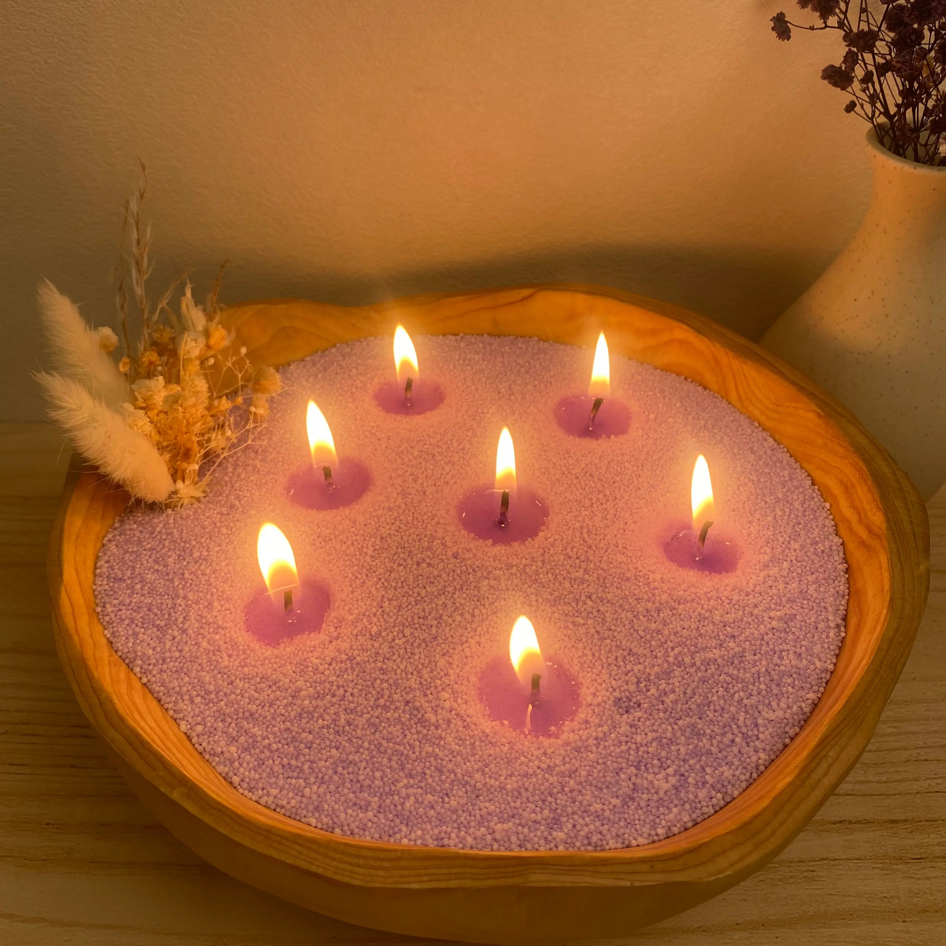 Lavender Purple pearled candle wax in a wooden candle bowl with soft flames and natural greenery.