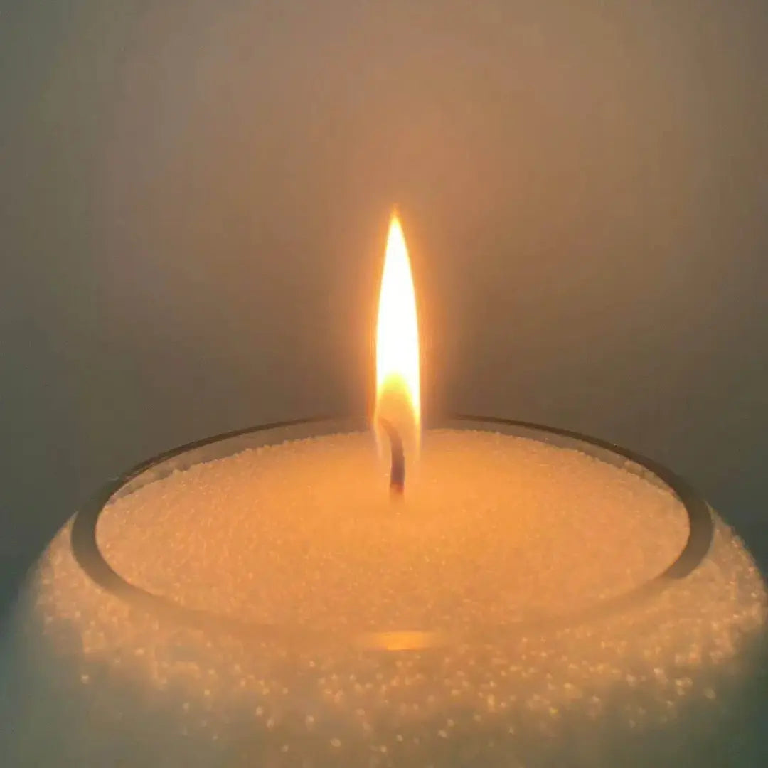 Soft White pearled candle wax close-up showing realistic wax beads, a cotton wick, and a warm candle flame.